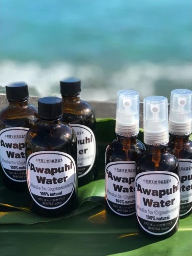 海辺に並べたAwapuhi Waterのボトルとスプレー